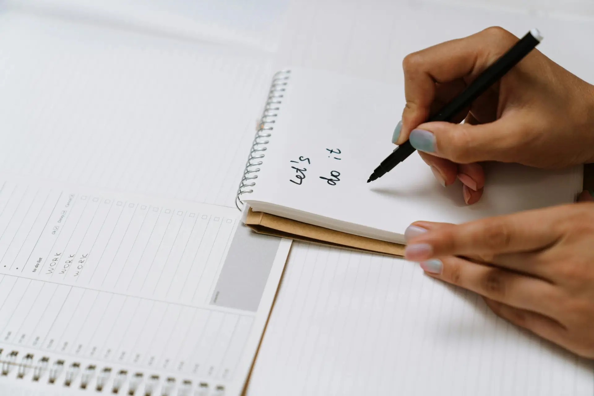 hands of a woman writing in a note book goals she is setting